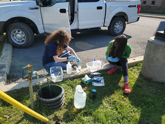Two people work with water quality equipment